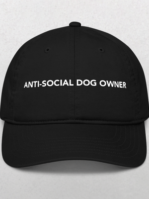 The Classic Organic Dad Cap - Anti-Social Dog Owners is a black hat with the words ANTI-SOCIAL DOG OWNER in bold white letters on the front, standing out against a plain, light-colored background.